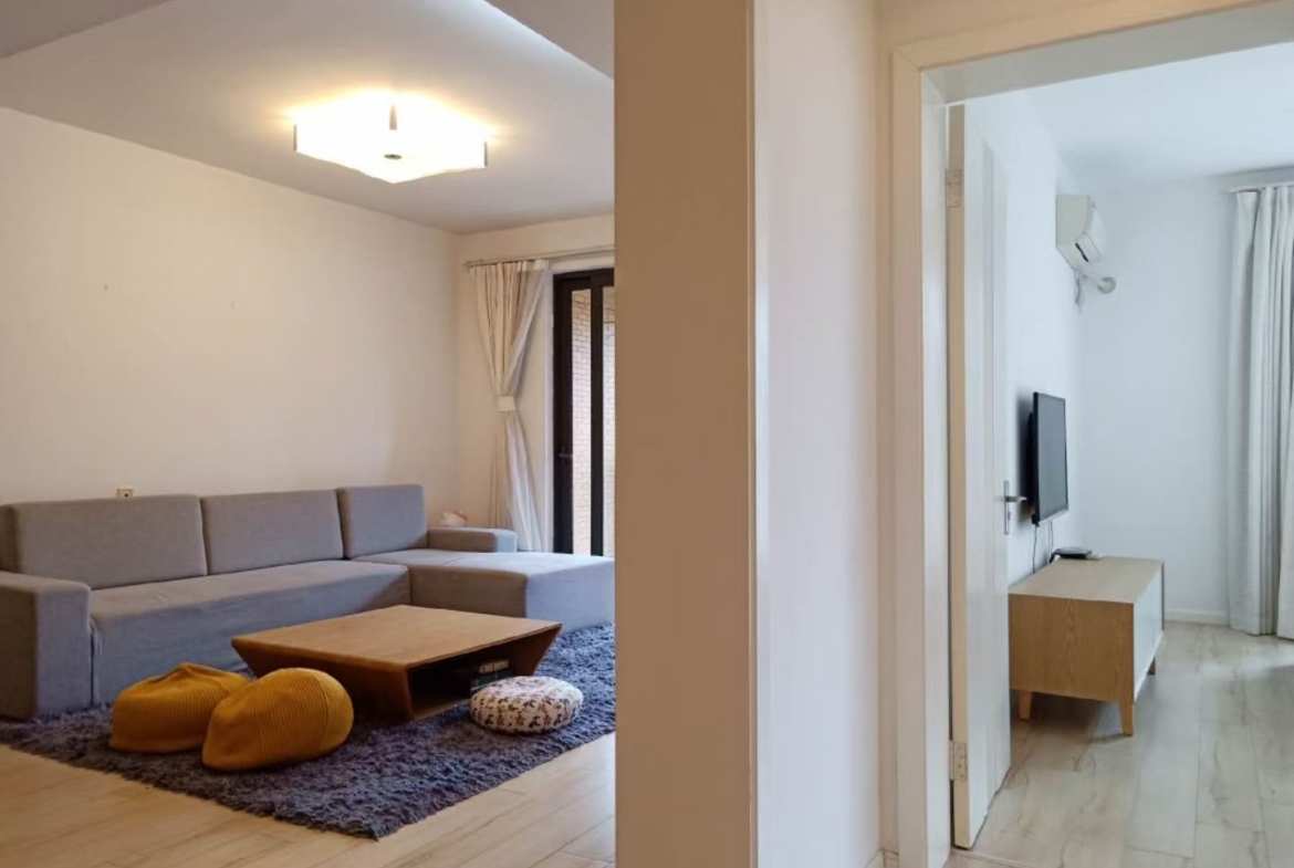 2-bed, 2-living, 1-bath unit at Territory Shanghai. 118 sqm, south-facing balcony, central Jing'an location near Nanjing West Road. 19,000 RMB/month.